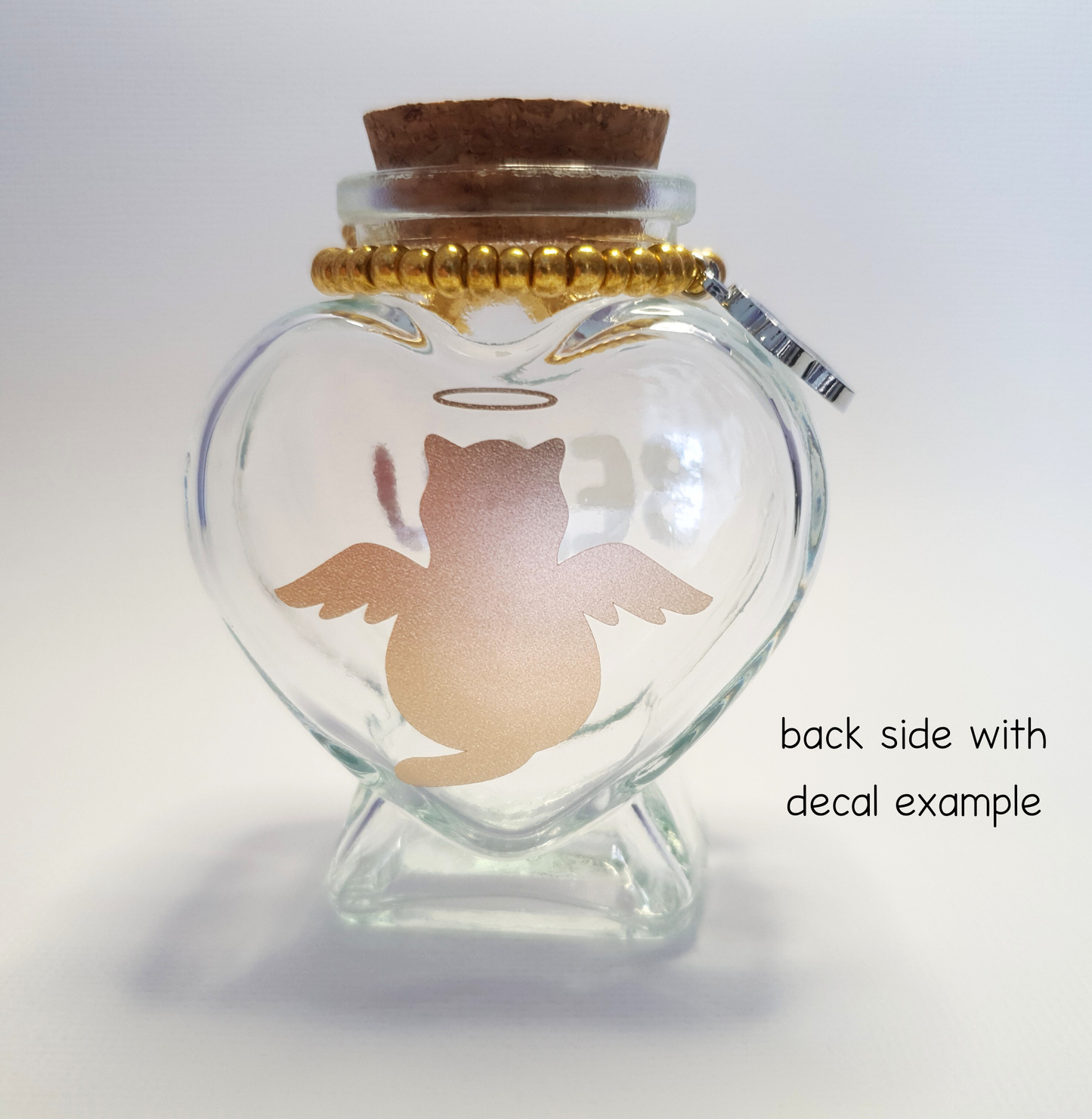 The photo displays the back of the bottle where a gold vinyl decal of a cat with wings and a halo has been placed.