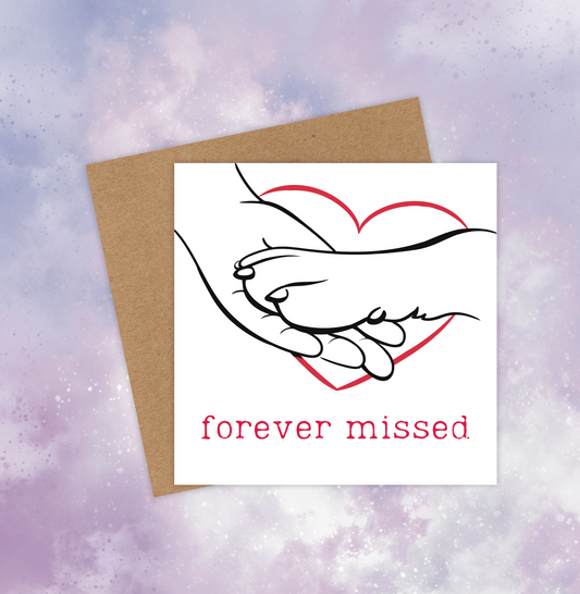 Sympathy card for a pet dog, featuring a dog paw placed on a human hand. A red heart outline surrounds the hand and paw. Below, the red text reads, “Forever missed.”