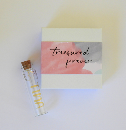 The outside of the box is wrapped in a glossy paper sleeve with a digital watercolour design and features the words, “treasured forever.”